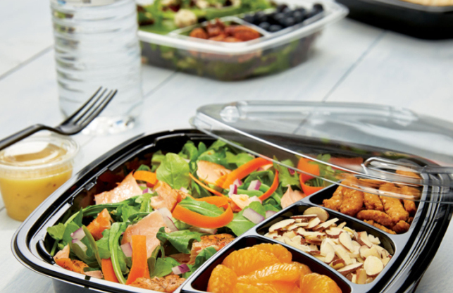 Colorful salad with mixed greens, vegetables, salmon, mandarin oranges, sliced almonds, and breaded chicken in a divided container
