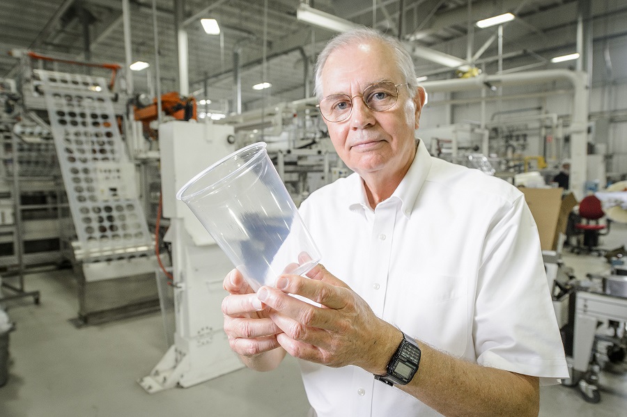 Older man in a factory holding a clear plastic container