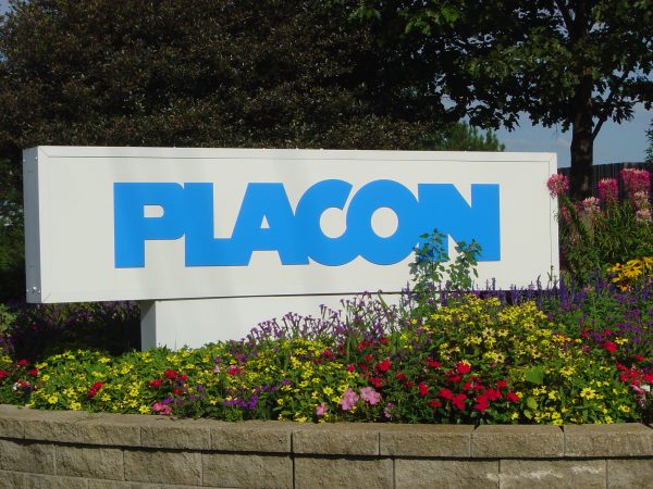 PLACON logo sign surrounded by colorful flowers in a landscaped garden