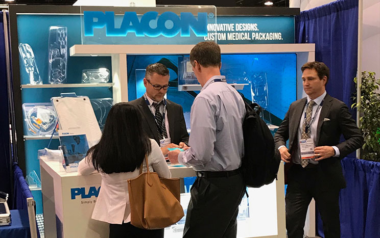 Attendees speak with exhibitors at a PAXON custom medical packaging trade show booth