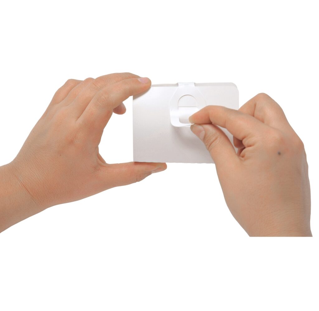 Hands opening a white plastic package by pulling its tab